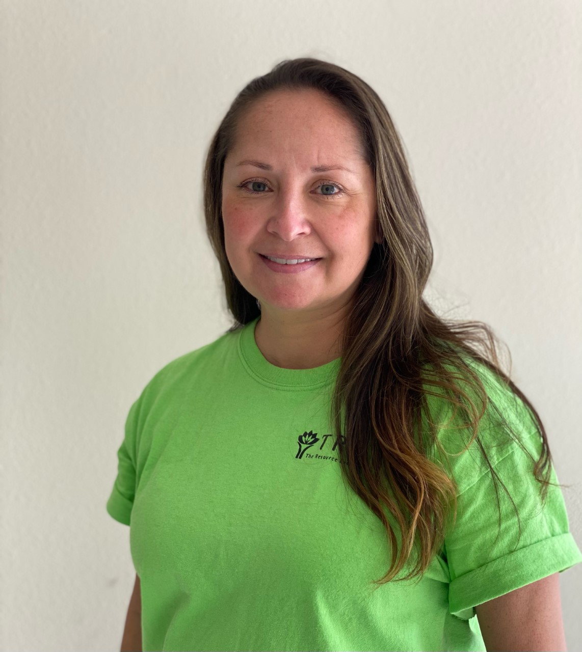 head shot of woman wearing green shirt smiling at the viewer