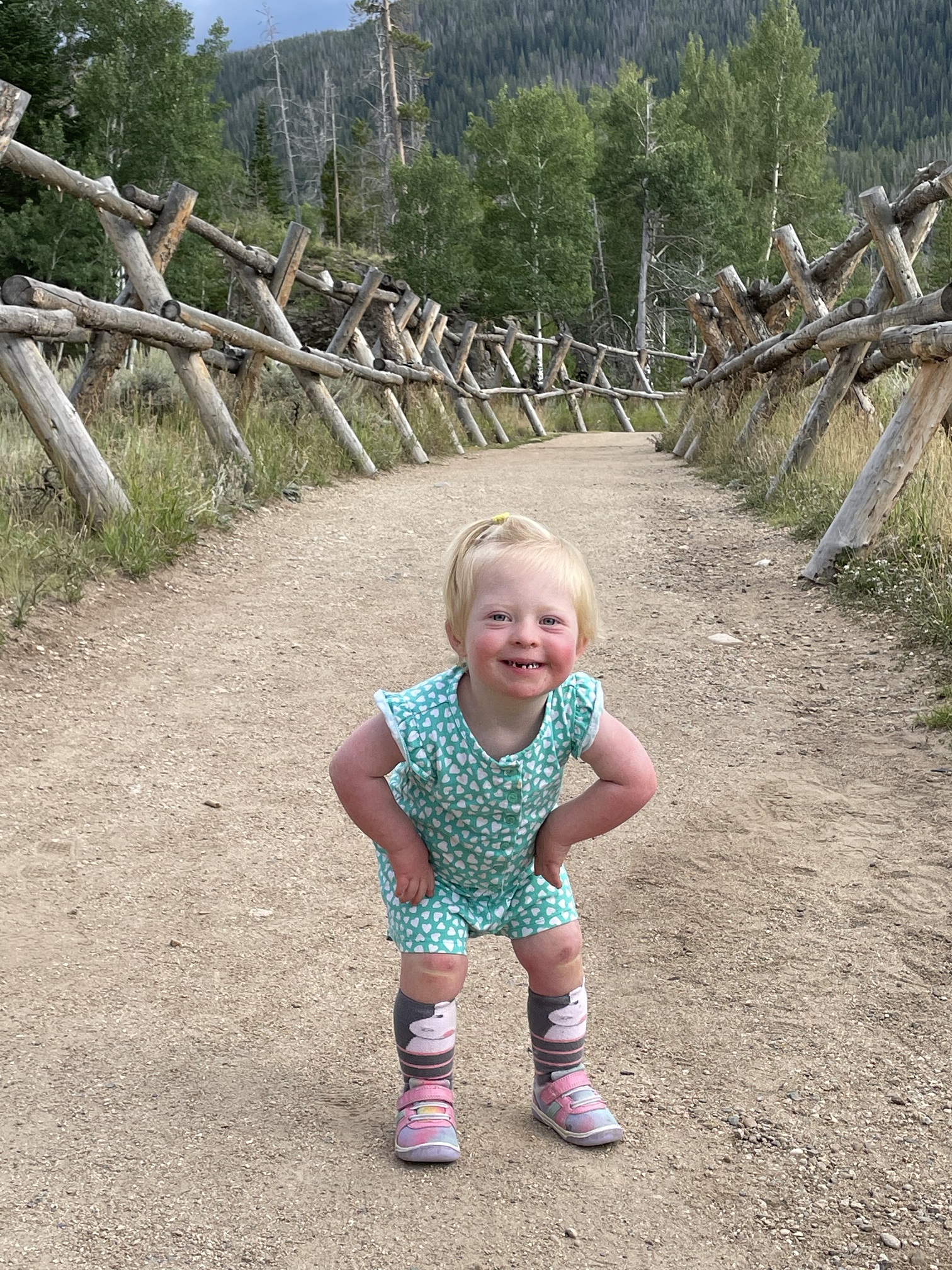 toddler outside with hands on hips smiling at viewer