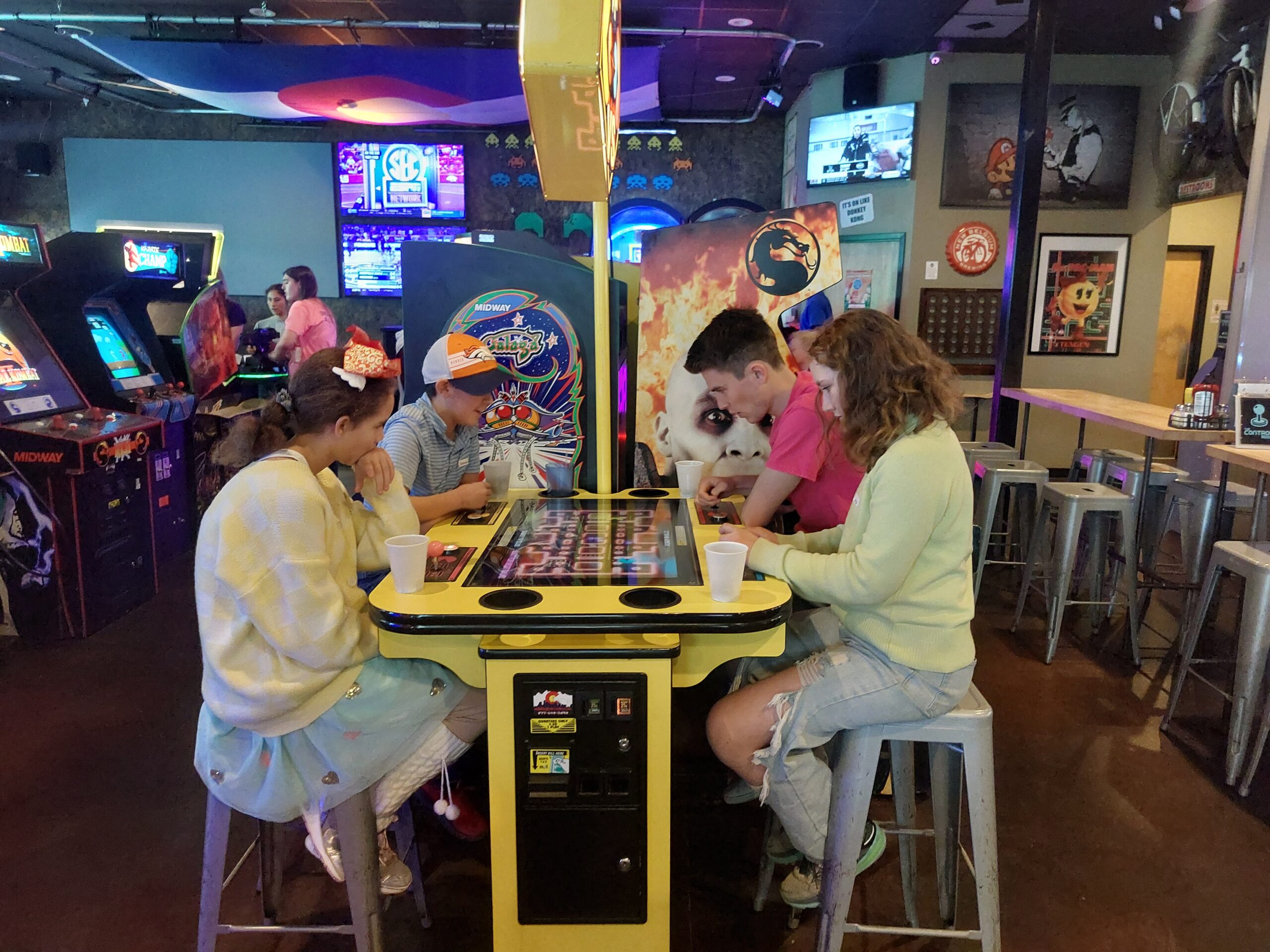 young adults play an electronic table game in an arcade