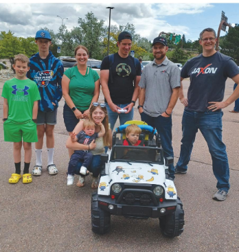 Nolan's family and team of volunteers pose for a photo with Nolan in his minion-themed miniature Jeep